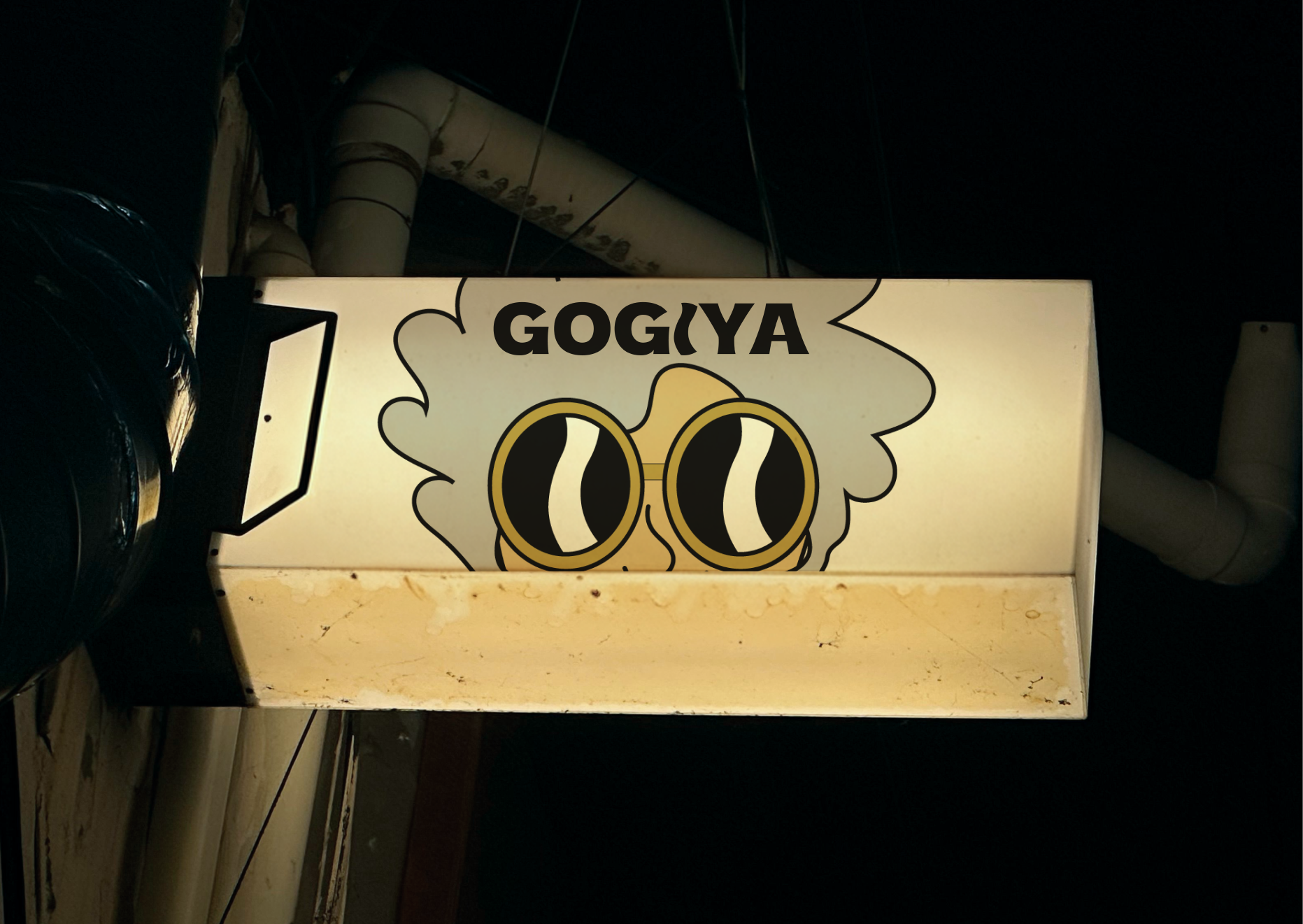 Gogiya illuminated restaurant sign mockup showing the grandmother character mark — oversized gold-rimmed glasses emerging from a grey hair cloud — backlit against a dark street.